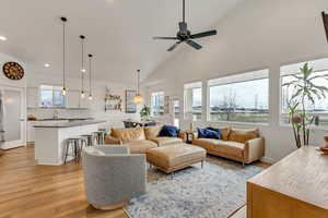 Living room featuring ceiling fan, sink, vaulted ceiling, and light wood-type flooring