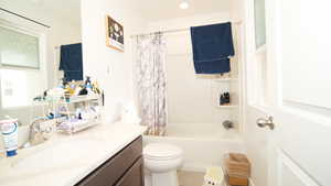 Full bathroom featuring shower / tub combo with curtain, vanity, and toilet