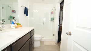 Bathroom featuring tile patterned floors, walk in shower, vanity, and toilet