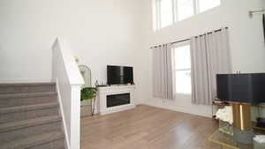 Unfurnished living room featuring a high ceiling and light hardwood / wood-style flooring