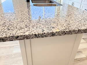 Room details featuring white cabinetry, light stone countertops, and sink