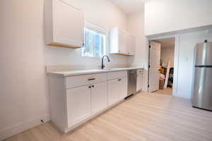 Kitchen featuring white cabinetry, sink, and stainless steel appliances