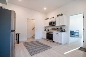 Kitchen featuring white cabinetry, appliances with stainless steel finishes, and light hardwood / wood-style flooring