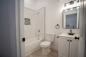 Full bathroom with vanity, hardwood / wood-style flooring, toilet, and tiled shower / bath