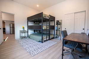 Bedroom with stainless steel refrigerator, a closet, and light hardwood / wood-style floors