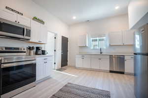 Kitchen featuring white cabinets, light wood-type flooring, and stainless steel appliances