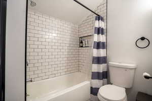 Bathroom with shower / bath combo, a textured ceiling, toilet, and vaulted ceiling