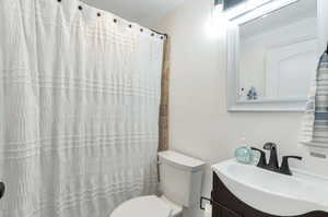 Bathroom with vanity, a shower with shower curtain, and toilet