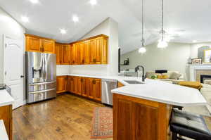 Kitchen with a tile fireplace, sink, stainless steel appliances, kitchen peninsula, and a breakfast bar