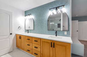 Bathroom featuring vanity, walk in shower, and backsplash