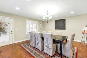 Dining room with a textured ceiling, an inviting chandelier, and dark wood-type flooring