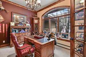 Carpeted office with crown molding, baseboard heating, and a chandelier