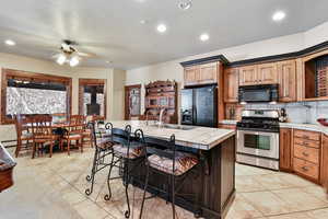 Kitchen with a kitchen breakfast bar, sink, black appliances, tile countertops, and a center island with sink