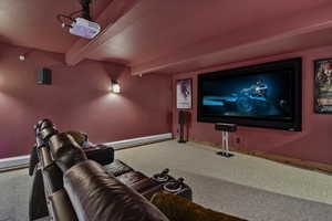 Home theater with beamed ceiling and carpet floors