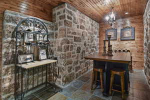 Wine area featuring a chandelier, wooden walls, and wood ceiling