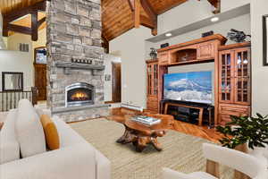 VIRTUALLY STAGED - Living room with high vaulted ceiling, a fireplace, a baseboard radiator, beam ceiling, and wood-type flooring