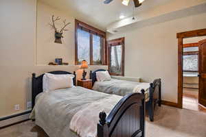 Bedroom featuring ceiling fan, light carpet, and a baseboard heating unit