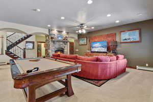 Recreation room featuring light colored carpet, ceiling fan, billiards, and a fireplace