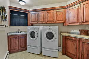 Clothes washing area with sink, cabinets, independent washer and dryer, and light tile patterned floors