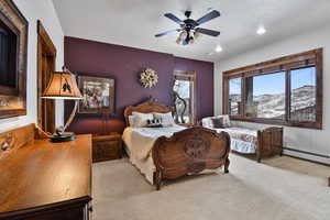 Bedroom with ceiling fan, a mountain view, light colored carpet