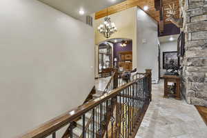 Hallway with beam ceiling, an inviting chandelier, a high ceiling