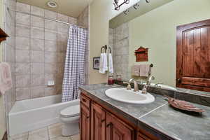 Full bathroom with tile patterned flooring, vanity, shower / tub combo with curtain, and toilet