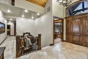 Hallway featuring a chandelier, high vaulted ceiling, and wooden ceiling