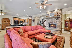 Living room with a ceiling fan, light colored carpet, and a fireplace