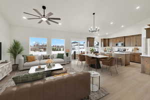 Living room with high vaulted ceiling, ceiling fan with notable chandelier, and light wood-type flooring