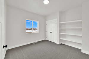 Unfurnished bedroom with dark colored carpet