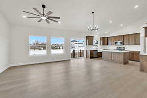 Kitchen with a kitchen island, appliances with stainless steel finishes, decorative light fixtures, lofted ceiling, and light hardwood / wood-style floors