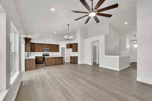 Kitchen featuring pendant lighting, sink, light hardwood / wood-style flooring, high vaulted ceiling, and a kitchen island