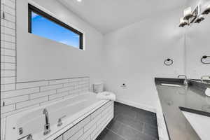 Full bath featuring a sink, baseboards, a garden tub, and tile patterned flooring