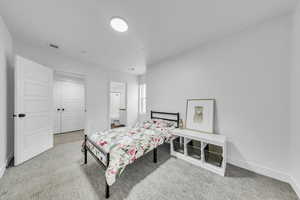Carpeted bedroom featuring baseboards, visible vents, and ensuite bathroom