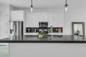 Kitchen with a sink, stainless steel appliances, dark countertops, and decorative backsplash