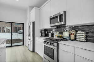 Kitchen featuring light countertops, white cabinets, and appliances with stainless steel finishes