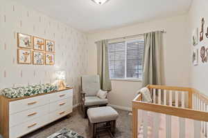 Carpeted bedroom featuring a crib