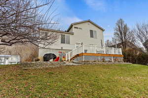 Back of house with a deck and a lawn