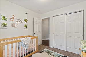 Bedroom featuring carpet, a closet, a textured ceiling, and a nursery area