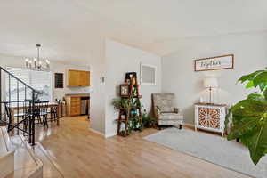 Living area with light hardwood / wood-style floors, lofted ceiling, and a chandelier