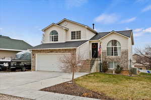 View of front property with central air condition unit, a front lawn, and a garage