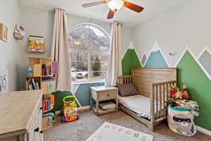 Bedroom with carpet floors, a nursery area, and ceiling fan