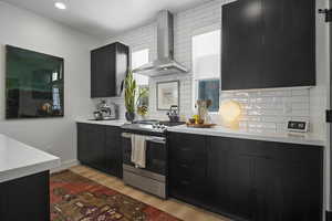 Contemporary elegant chef's kitchen featuring quartz countertops, decorative light fixtures, stainless steel GE appliances, gas range, direct-vent hood, farmhouse sink, backsplash, and sleek flat-panel cabinetry