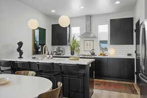 Contemporary elegant chef's kitchen featuring quartz countertops, decorative light fixtures, stainless steel GE appliances, gas range, direct-vent hood, farmhouse sink, backsplash, and sleek flat-panel cabinetry