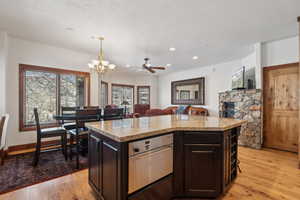 Kitchen featuring a center island, ceiling fan with notable chandelier, decorative light fixtures, light hardwood / wood-style floors, and dark brown cabinets