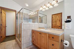 Bathroom with tile patterned flooring, vanity, toilet, and a shower with door