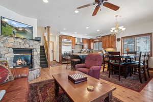 Living room with a fireplace, ceiling fan with notable chandelier, light hardwood / wood-style flooring, and sink