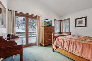 Carpeted bedroom with multiple windows and vaulted ceiling