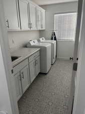 Laundry room featuring washer and clothes dryer, cabinets, and sink