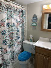 Bathroom featuring tile patterned floors, vanity, toilet, and a shower with curtain